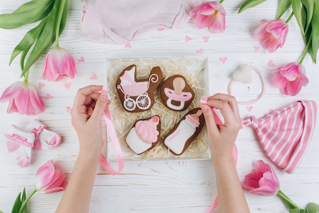 Mains féminines tenant la boîte avec des cookies. Une composition pour les nouveau-nés