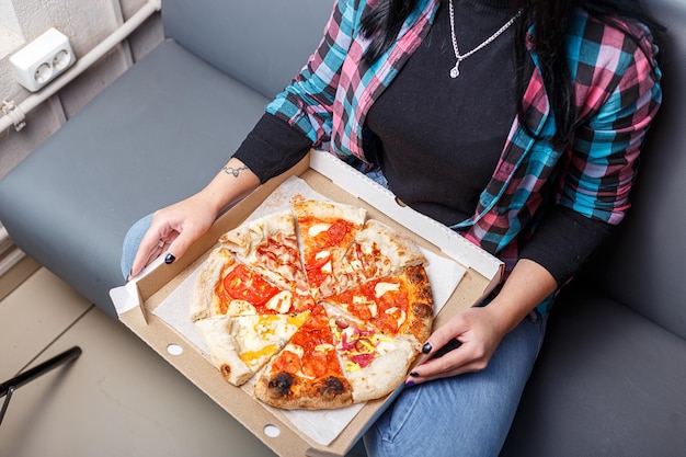 mains féminines, tenant une boîte avec différents types de pizzas, mangeant, mordant et déchirant, léger et da