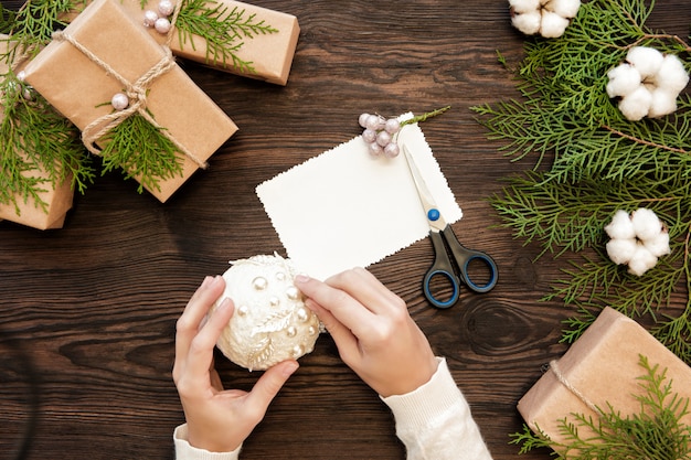 Mains féminines tenant une boule de Noël. Fabrication de jouets de Noël faits à la main