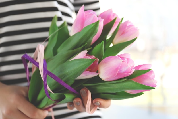 Mains féminines tenant un bouquet de tulipes roses se bouchent