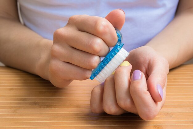 Mains féminines tenant une brosse à ongles