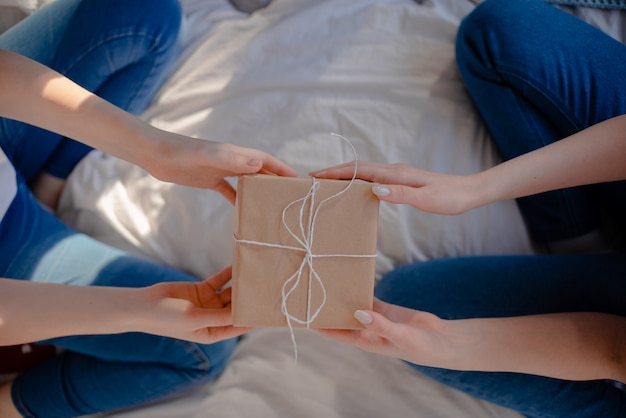 Mains Féminines Tenant Cadeau. Présent Enveloppé De Papier Kraft.