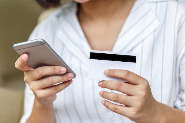 Mains féminines tenant une carte de crédit et utilisant un smartphone Concept d'achats en ligne Paiement en ligne