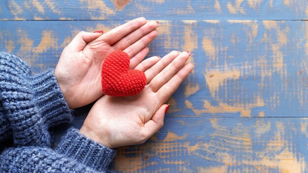 Mains Féminines Tenant Un Coeur Rouge Tricoté à La Main. Vue De Dessus