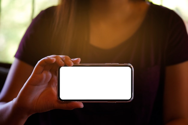 Mains féminines tenant un écran blanc de téléphone portable vers l&#39;avant pour l&#39;écran de copie d&#39;espace