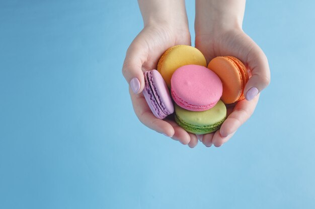 Mains féminines tenant des macarons français colorés