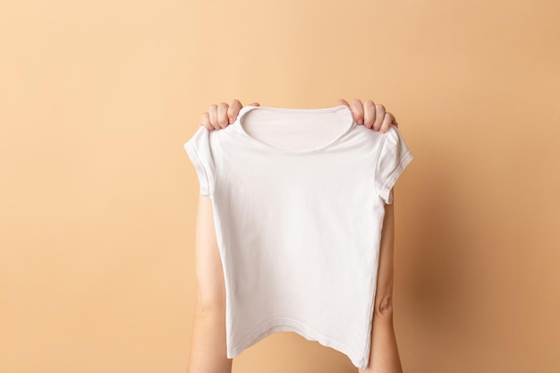 Mains féminines tenant une maquette de gros plan de t-shirt blanc