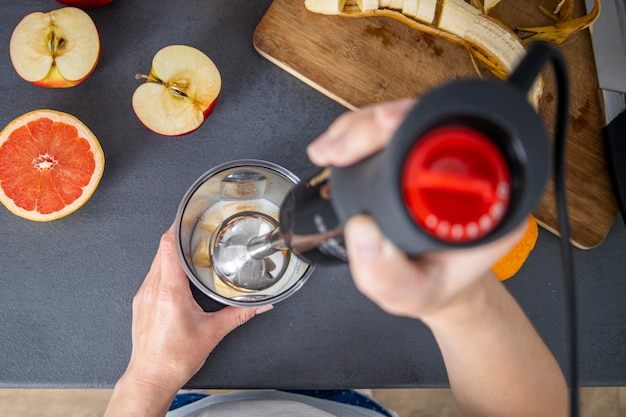 Mains féminines tenant un mélangeur à main pour mélanger des smoothies aux fruits frais dans la cuisine Vue de dessus mise à plat