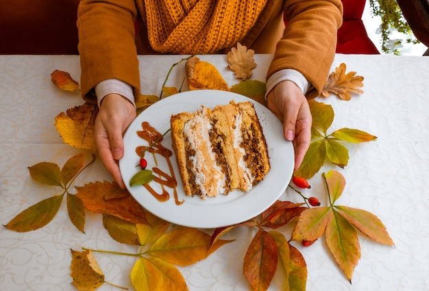 Mains féminines tenant la plaque blanche avec un gâteau