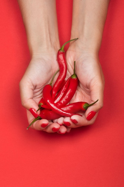 Mains féminines tenant une poignée de piments rouges frais