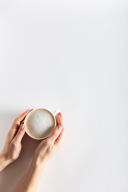 Mains féminines tenant une tasse de café sur un fond structurel blanc Espace de copie