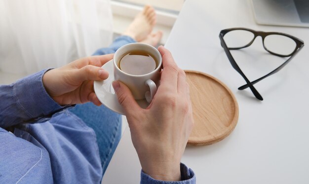 Mains féminines tenant une tasse de café ou de thé chaud