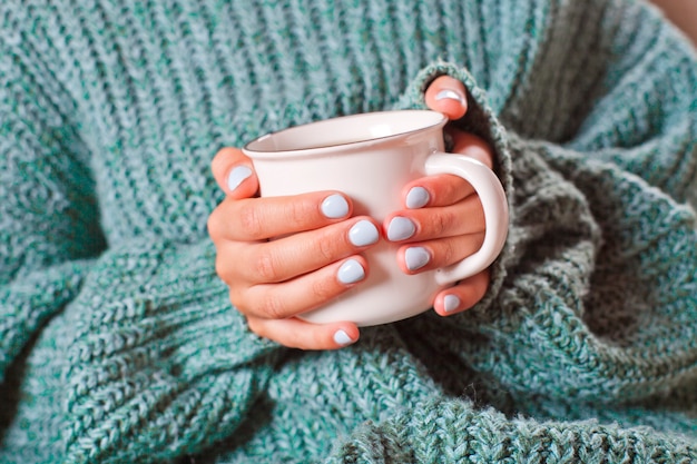 Mains féminines tenant une tasse de café ou de thé