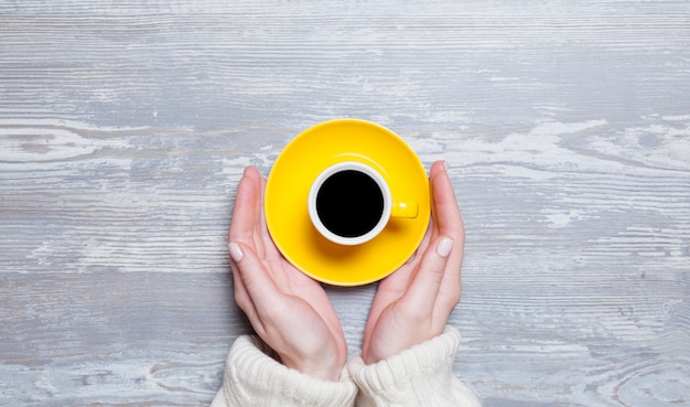 Mains féminines tenant une tasse de café.