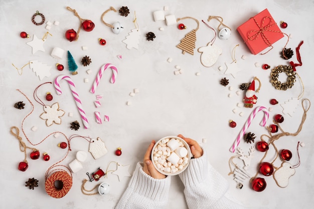 Des mains féminines tenant la tasse de chocolat chaud décorées de guimauves. Thème de noël