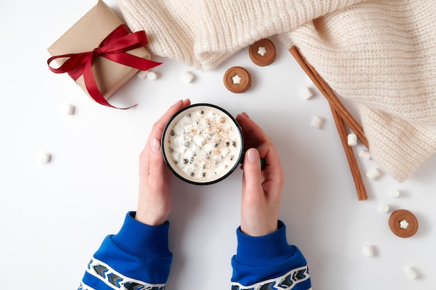 Mains féminines tenant une tasse de chocolat chaud à la guimauve