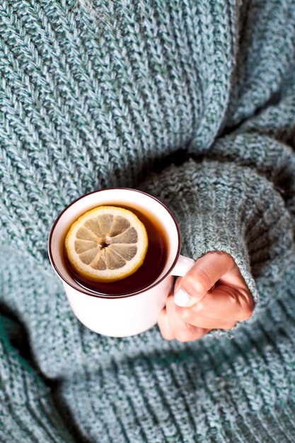 Mains féminines tenant une tasse de thé chaud au citron
