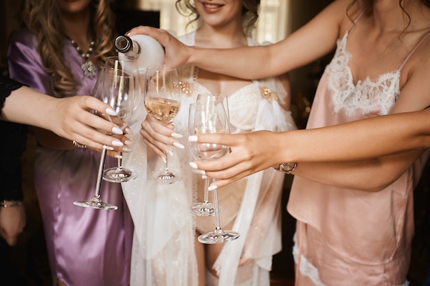 Mains féminines tenant des verres de champagne à la partie de poule. Mariée et demoiselles d'honneur griller avec du champagne et s'amuser le matin du mariage. La photo en gros plan de filles célébrant une partie de bachelorette.