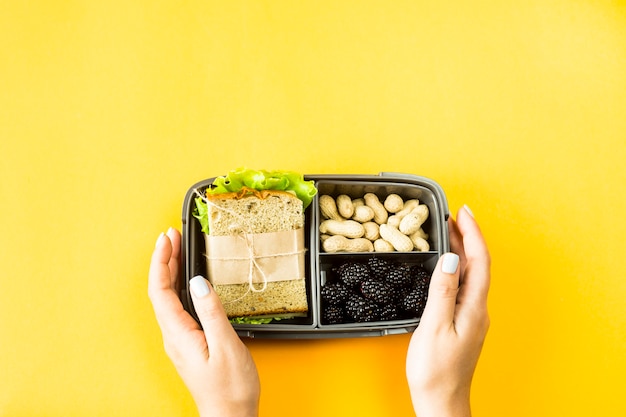 Mains féminines tenir la boîte à lunch avec de la nourriture