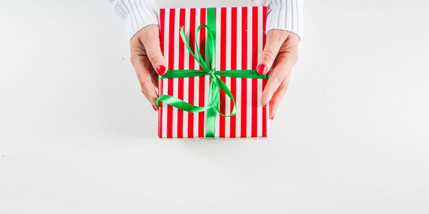 Des mains féminines tiennent des coffrets cadeaux de Noël, du champagne et des verres