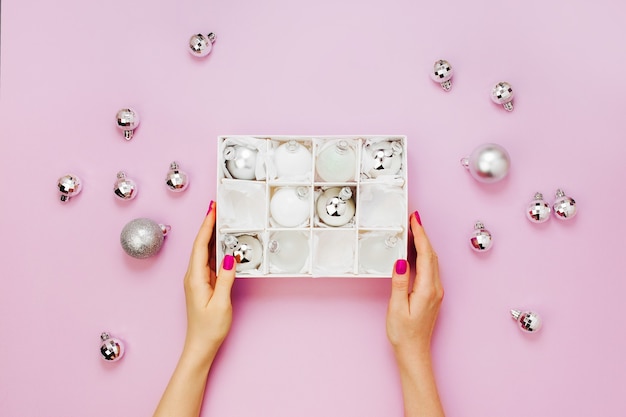 Les mains féminines tiennent un ensemble élégant de boules de Noël argentées brillantes. Concepts de vacances. Mise à plat, vue de dessus