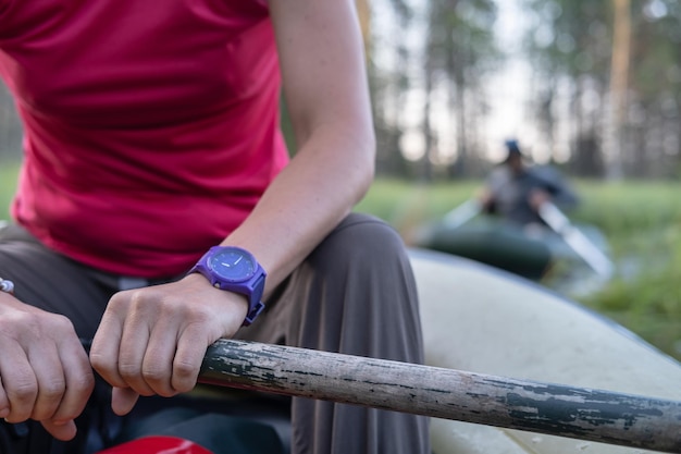 Les mains féminines tiennent une pagaie dans un bateau gonflable dans les canaux entre les lacs sur un arrière-plan flou