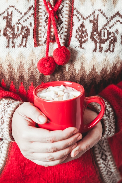 Les mains féminines tiennent une tasse de cacao avec de la guimauve