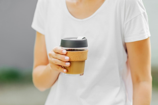 Les mains féminines tiennent une tasse à café réutilisable. Emportez votre café à emporter avec une tasse de voyage réutilisable. Zero gaspillage. Concept de mode de vie durable.