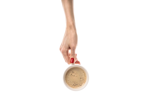 Mains féminines tiennent une tasse en céramique blanche sur fond blanc Tasse à café tasse avec café latte cappuccino café trois en un Mains féminines avec manucure rouge fraîche Isolé sur fond blanc
