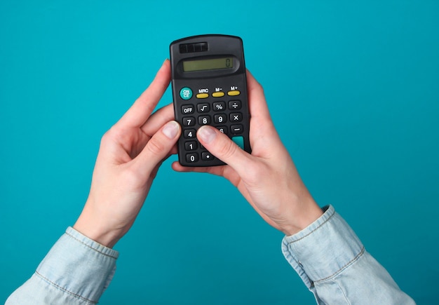 Les mains féminines utilisent la calculatrice sur un bleu.