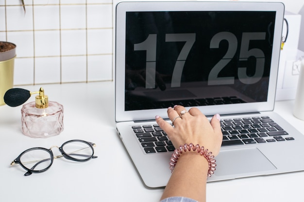 Des mains féminines utilisent un clavier d'ordinateur portable sur une table blanche