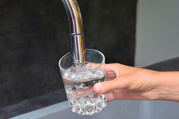 Mains féminines versant de l'eau dans une tasse en verre