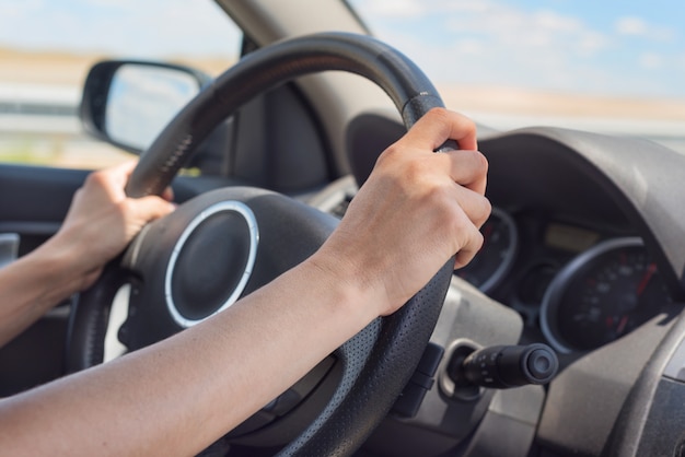 Mains féminines sur le volant d&#39;une voiture en conduisant