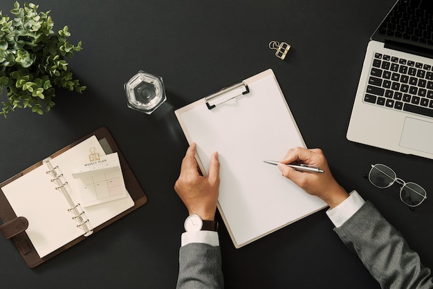 Mains de femme d'affaires signant un document de contrat assis à table de bureau