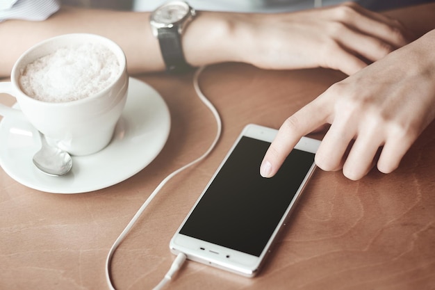 Photo mains de femme d'affaires avec téléphone intelligent et tasse de café. pour le montage d'affichage graphique.