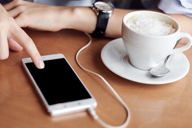 Mains de femme d'affaires avec téléphone intelligent et tasse de café. Pour le montage d'affichage graphique.