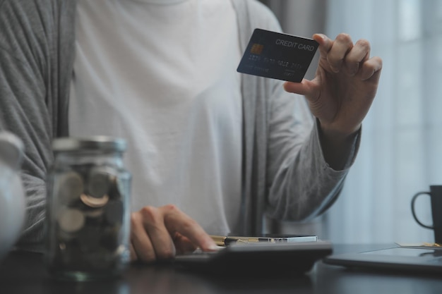 Des mains d'une femme d'affaires tenant une carte de crédit et utilisant une carte de crédits pour faire des achats en ligne.