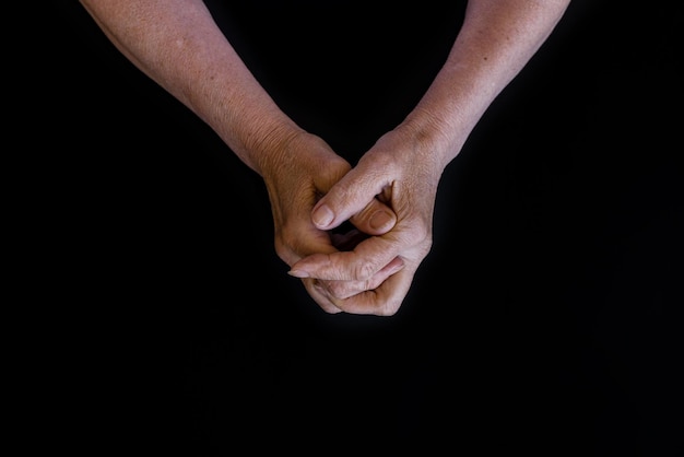 Mains d'une femme âgée dans les rides sur un fond noir closeup copypaste