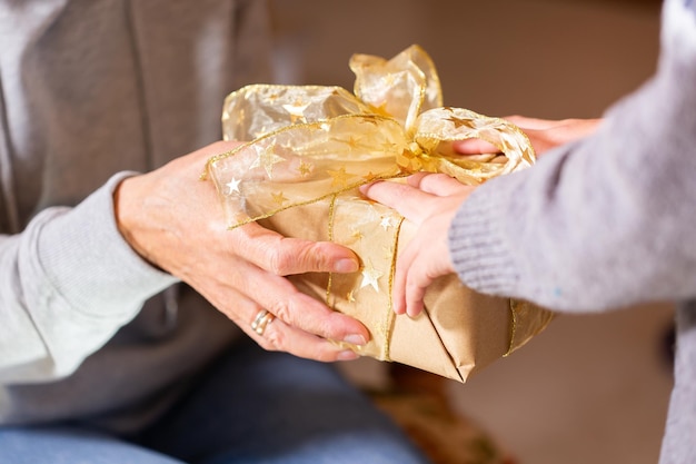 Mains d'une femme âgée et d'un enfant tenant un cadeau de Noël