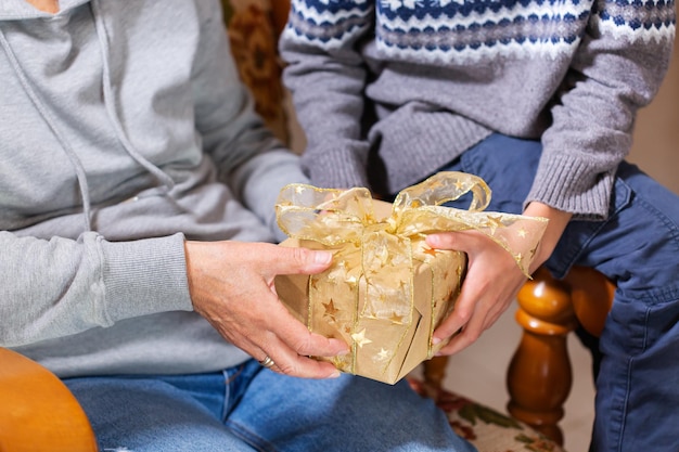 Mains d'une femme âgée et d'un enfant tenant un cadeau de Noël