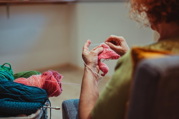 Mains d'une femme âgée tricotant à la maison