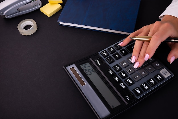 Les mains de la femme à l'aide d'une calculatrice sur un bureau