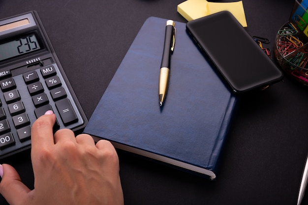 Les mains de la femme à l'aide d'une calculatrice sur un bureau