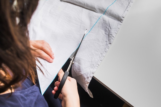 Les mains d'une femme à l'aide de ciseaux de couture