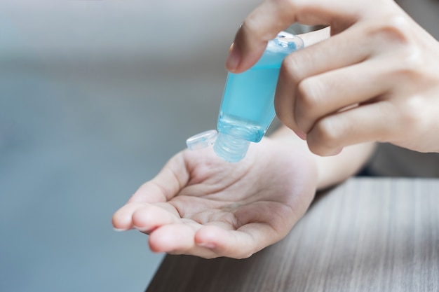 Mains de femme à l'aide du distributeur de gel désinfectant pour les mains