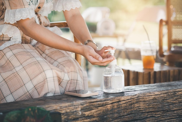 Mains de femme à l'aide de gel d'alcool pour les mains ou d'un distributeur de bouteilles de désinfectant contre le virus corona Covid19 dans un café Concept antiseptique d'hygiène et de santé Prévention de l'épidémie de virus pandémique