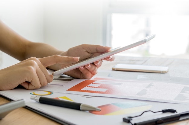 Mains de la femme à l&#39;aide de tablette numérique avec document financier.