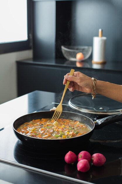 Mains de femme ajoutant des ingrédients dans un ragoût de légumes