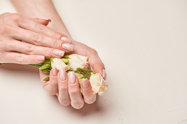 Mains de femme avec une belle manucure sur fond clair