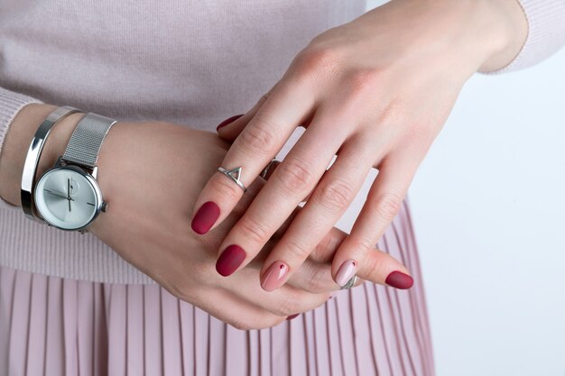 Mains de femme avec des bijoux et accessoires en argent. Fille avec une conception de manucure minimaliste printemps été rose.